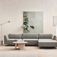 Gray sectional sofa with clean lines and subtle texture, set against a soft, neutral background and greenery.