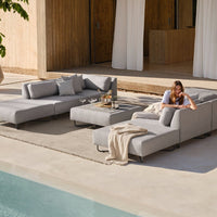 Gray sectional sofa with a sleek, modern design, featuring light cushions and a neutral palette for outdoor comfort.