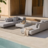 Light gray outdoor sectional sofa with sleek lines and soft cushions, paired with a neutral-toned throw blanket.