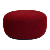Round ottoman in rich burgundy upholstery with a textured finish, perfect for adding a pop of color to any space.