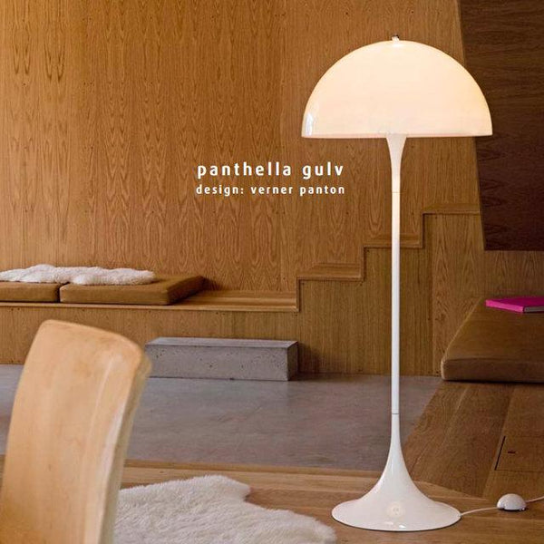 White floor lamp with a smooth, rounded shade, set against natural wood textures in warm tones.