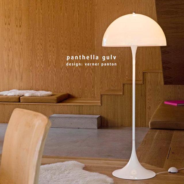 White floor lamp with a smooth, rounded shade, set against natural wood textures in warm tones.