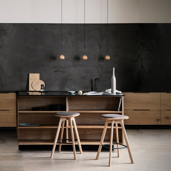 "Modern kitchen with a black wall, light wood cabinetry, and minimalist bar stools in natural wood tones."