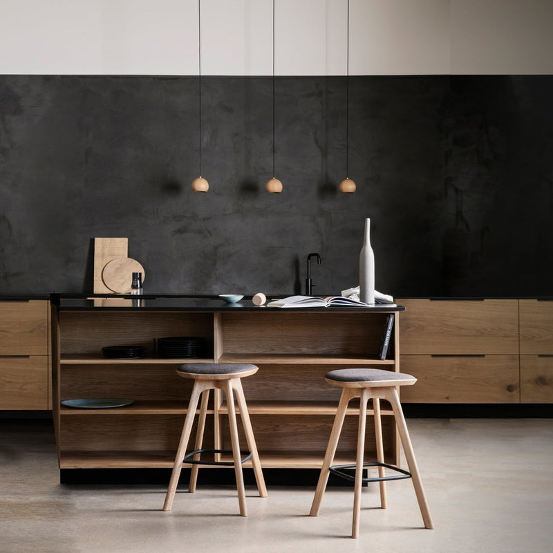 "Modern kitchen with a black wall, light wood cabinetry, and minimalist bar stools in natural wood tones."