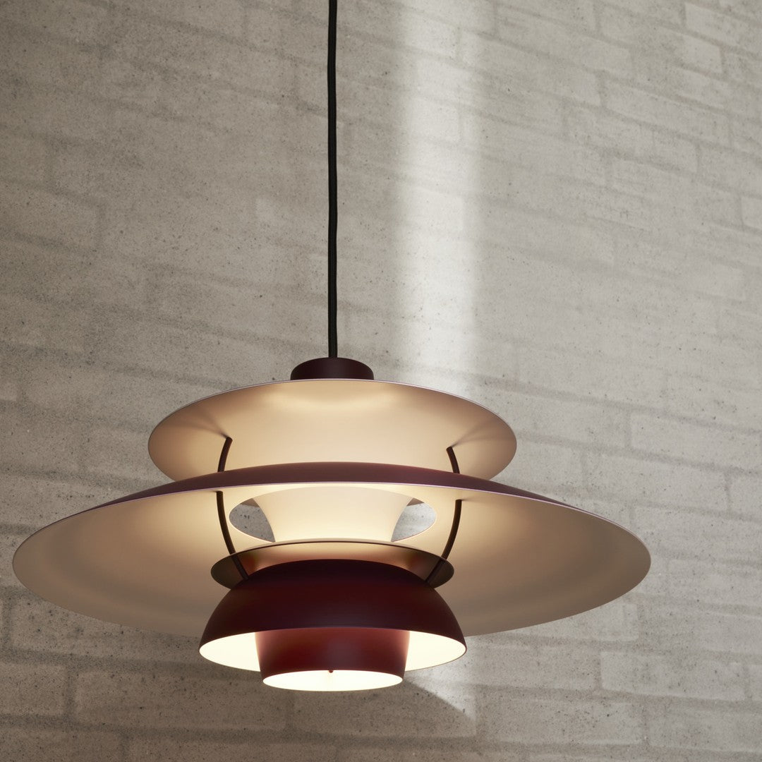 Modern pendant lamp featuring layered circular shades in warm red and soft white hues, against a textured gray background.