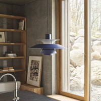 Modern pendant lamp in deep blue and translucent white, featuring sleek layered design, set against a natural backdrop.
