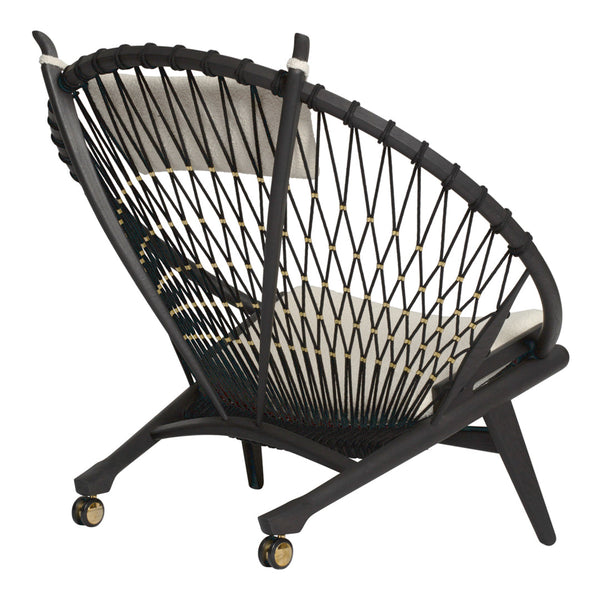 Black woven chair with a unique geometric pattern and cream cushions, featuring stylish wheels for easy mobility.