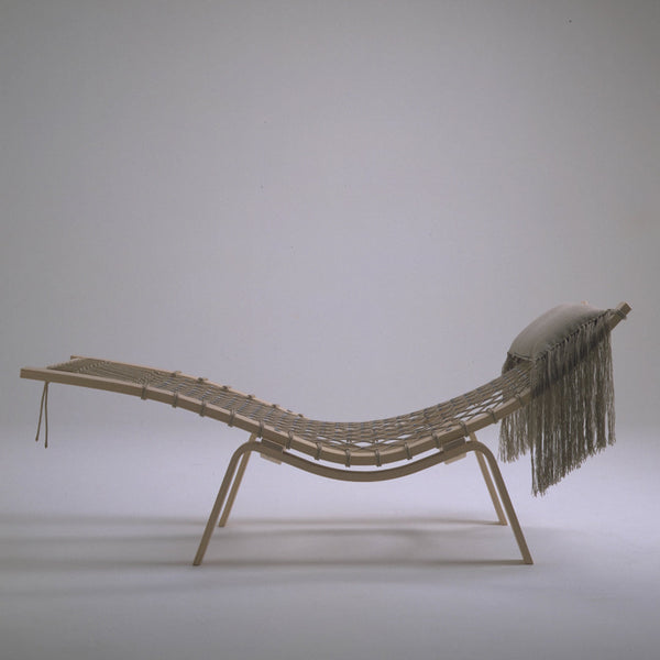 Natural wood lounge chair with a minimalist woven design and soft, fringe accent. Neutral colors enhance the aesthetic.