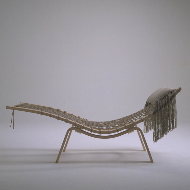Natural wood lounge chair with a minimalist woven design and soft, fringe accent. Neutral colors enhance the aesthetic.