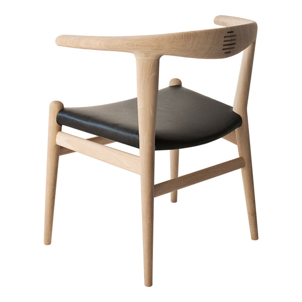 Light wood chair with a sleek black leather seat and minimalist design, showcasing natural grains and smooth lines.