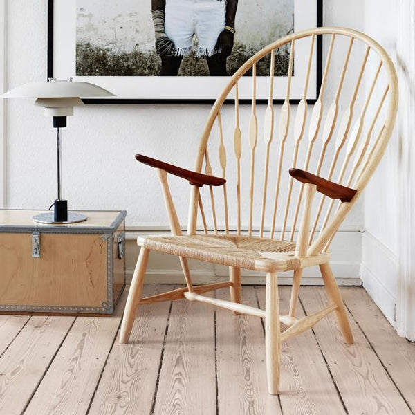 Natural wood chair with a light finish, featuring a unique spoked back and dark wood armrests, complementing a modern interior.