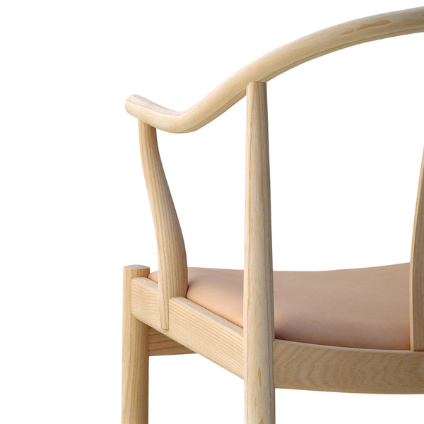 Light wood chair with smooth, curved lines and a soft peach upholstered seat, showcasing a minimalist design.