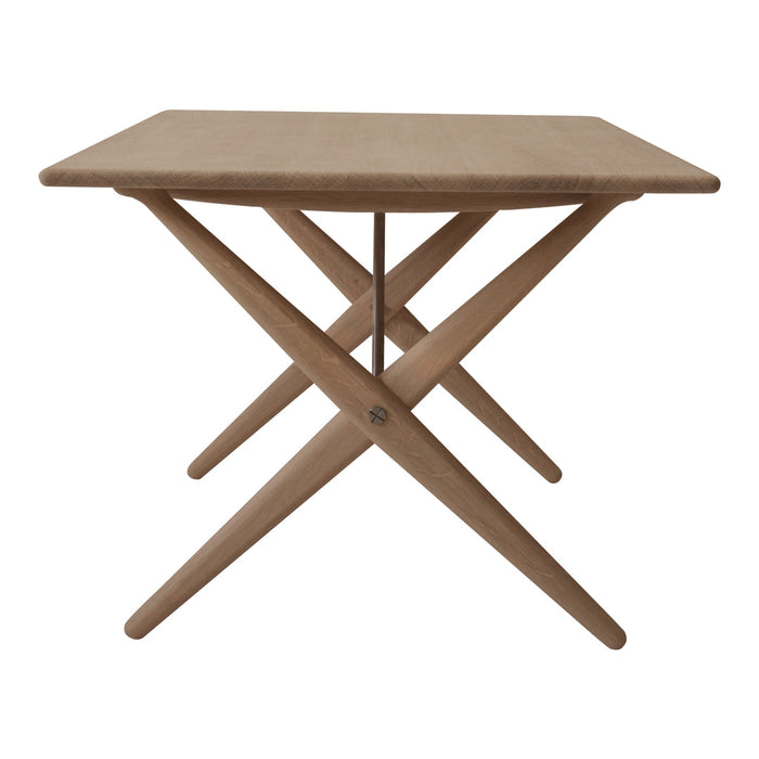 Light brown wooden table with a simple, clean design and crossed legs, perfect for modern dining or decor.