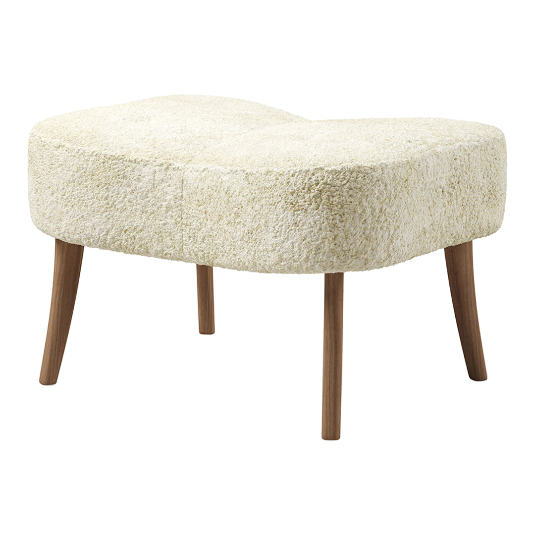 Cream-colored, fluffy upholstered ottoman with a unique curved shape and wooden legs, offering a cozy aesthetic.