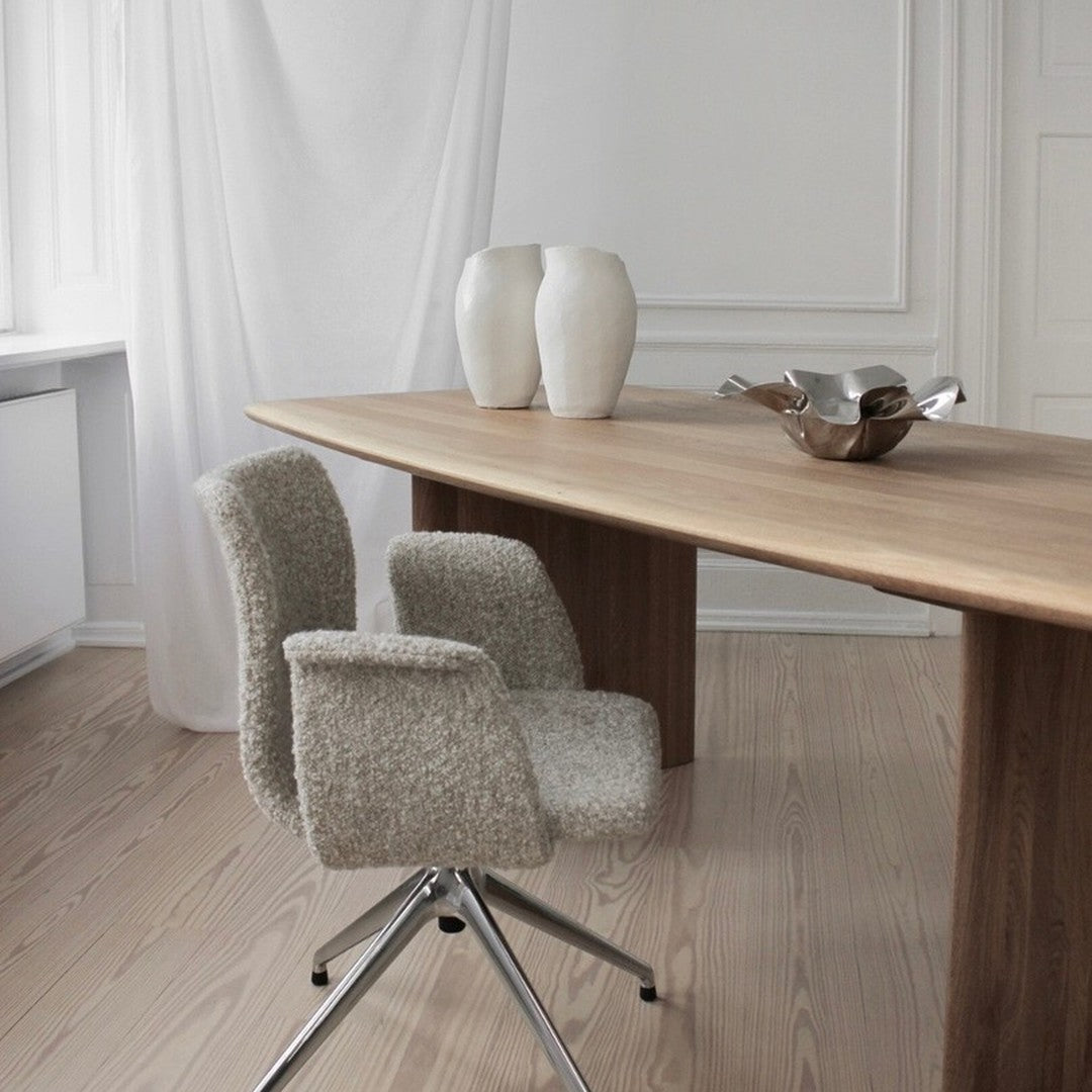 Light beige modern chairs on a wooden table, accented by white ceramic vases against a minimalist backdrop.