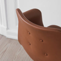 Brown leather chair with a smooth finish and button-tufted detail, perfect for modern decor.