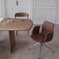 "Modern brown swivel chair with smooth curves and chrome details, paired with a simple wooden table in a light interior."