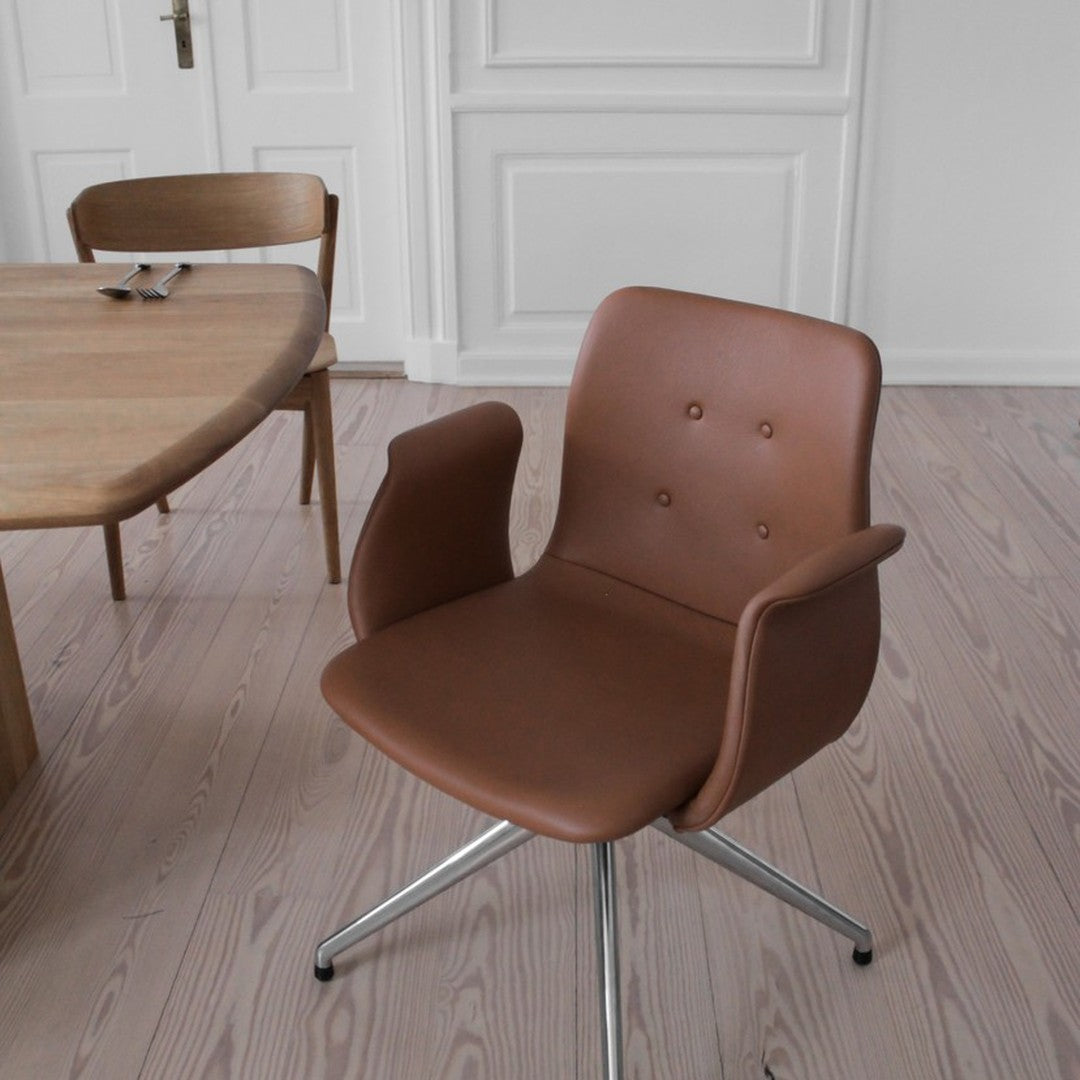 Brown faux leather chair with a smooth surface and subtle button detailing, set against a light wooden floor.