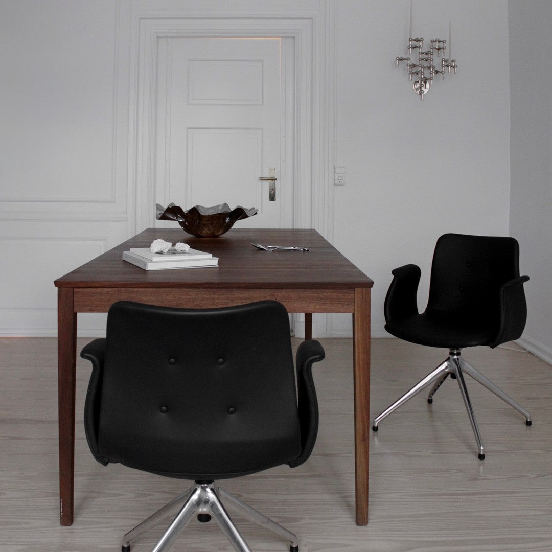Minimalist wooden table with a textured surface, paired with sleek black chairs and subtle metallic accents.