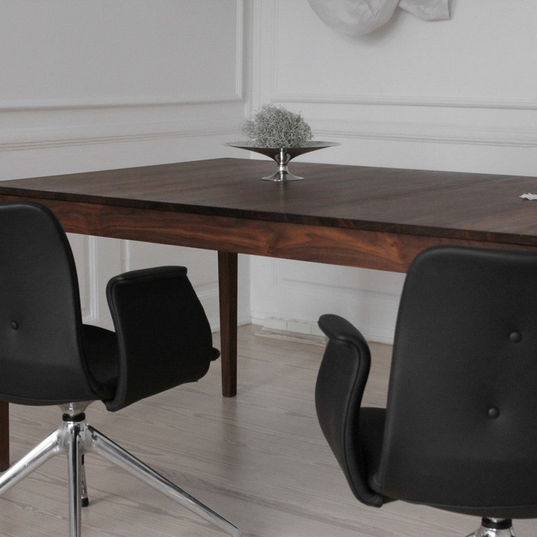 Elegant dark wood table with sleek black chairs, minimalistic design against a light, neutral backdrop.