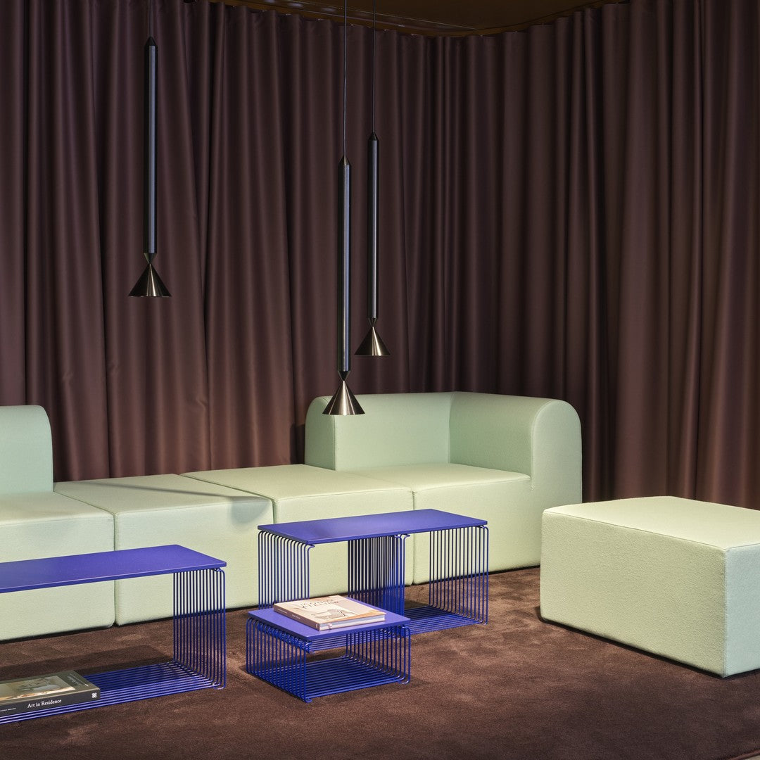 Soft mint green sofa with sleek blue tables, set against rich purple curtains for a modern, stylish contrast.