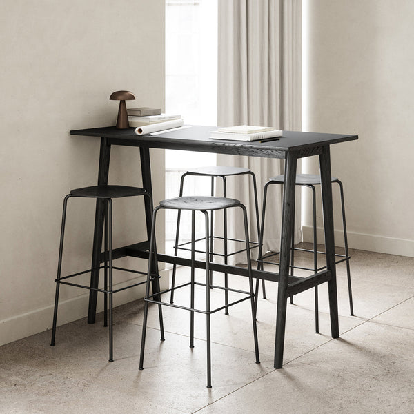 Modern black bar table and stools with sleek lines and minimalistic design against a neutral-toned background.