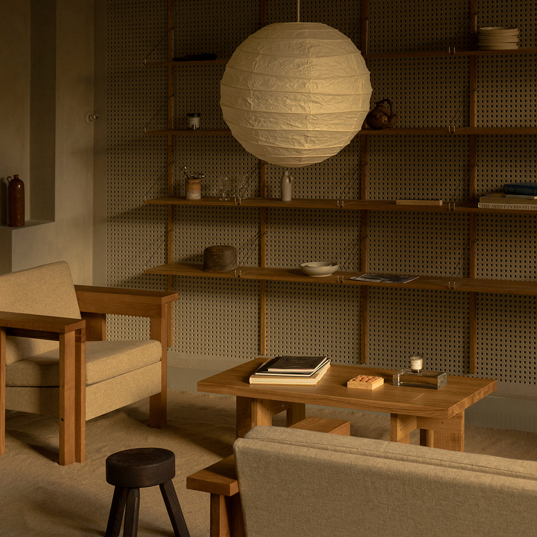 Warm neutral tones with textured wood accents and soft beige upholstery, featuring a round paper pendant light.