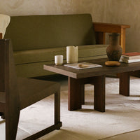 Olive green sofa, dark wooden coffee table, neutral beige rug, and earthy pottery create a warm, inviting interior.