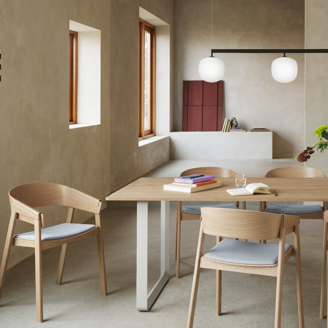 Light wooden dining table and chairs with soft blue cushions in a neutral-toned room featuring earthy textures.