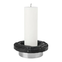White candle on a black marble holder with silver base, featuring sleek, modern design elements.