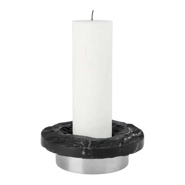 White candle on a black marble holder with silver base, featuring sleek, modern design elements.