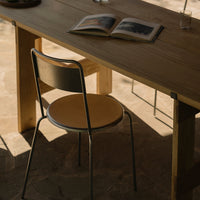 "Minimalist wooden table with a simple metal chair in warm tones, featuring natural textures and soft shadows."