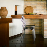 Modern chrome chairs with black seats, set against a warm wooden backdrop and textured brick wall. Perfect for contemporary decor.