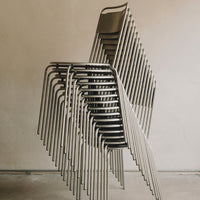 Stacked metal chairs with sleek, minimalist design in silver and gray tones, showcasing modern simplicity.