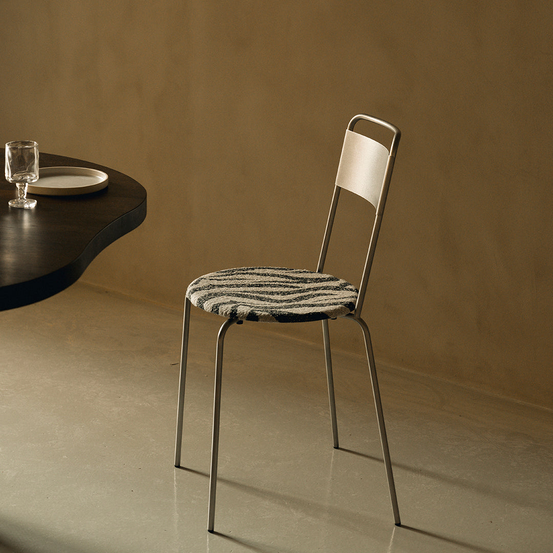 Modern chair with a striped black and white seat, complemented by a sleek silver metal frame. Perfect for minimalist decor.