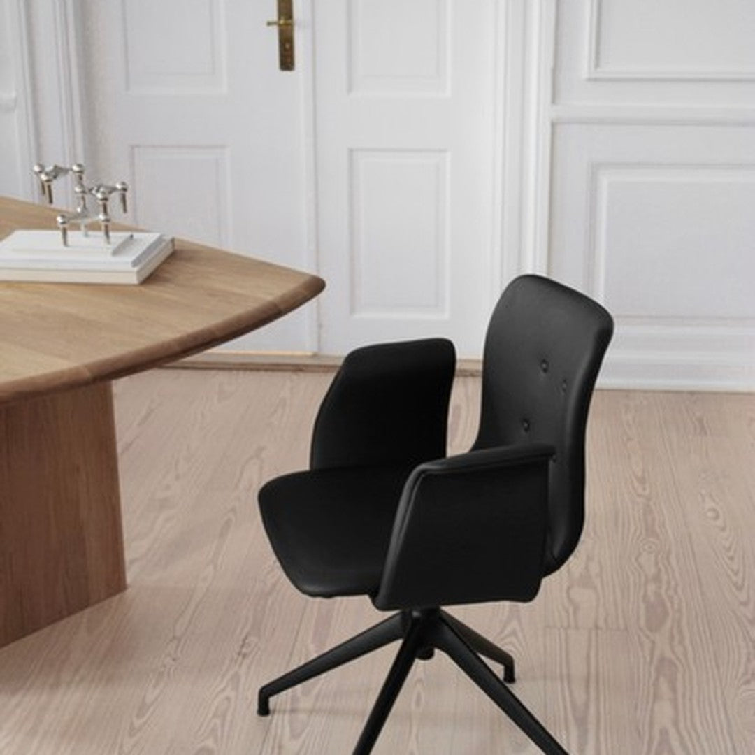 Black ergonomic chair with smooth lines, set against a minimalist wooden table and light-colored floor.