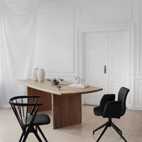 Modern dining space featuring a light wooden table, black chairs, and neutral-colored decor in a minimalist design.
