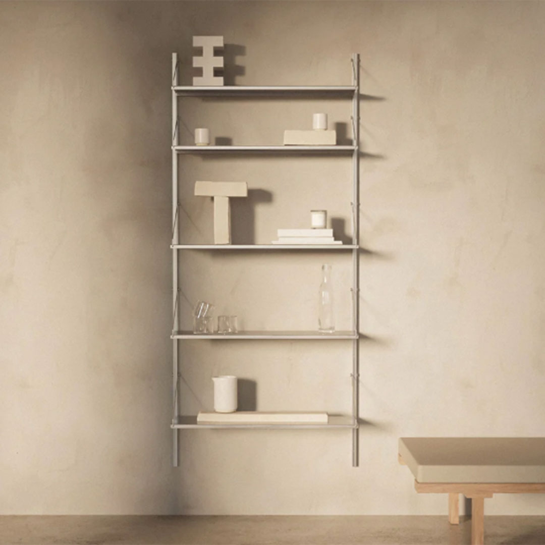 Modern gray shelving unit with a minimalist design, featuring various white decorative objects against a textured wall.