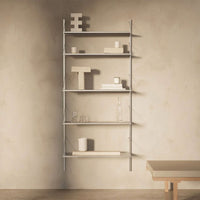 Modern gray shelving unit with a minimalist design, featuring various white decorative objects against a textured wall.