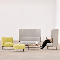 Modern gray upholstered sofa with vibrant yellow accent chairs and ottoman in a minimalist setting.