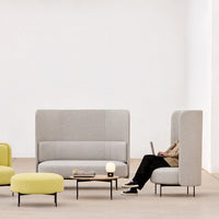 Gray upholstered seating with a textured finish, paired with bright yellow accents and minimalist black legs.