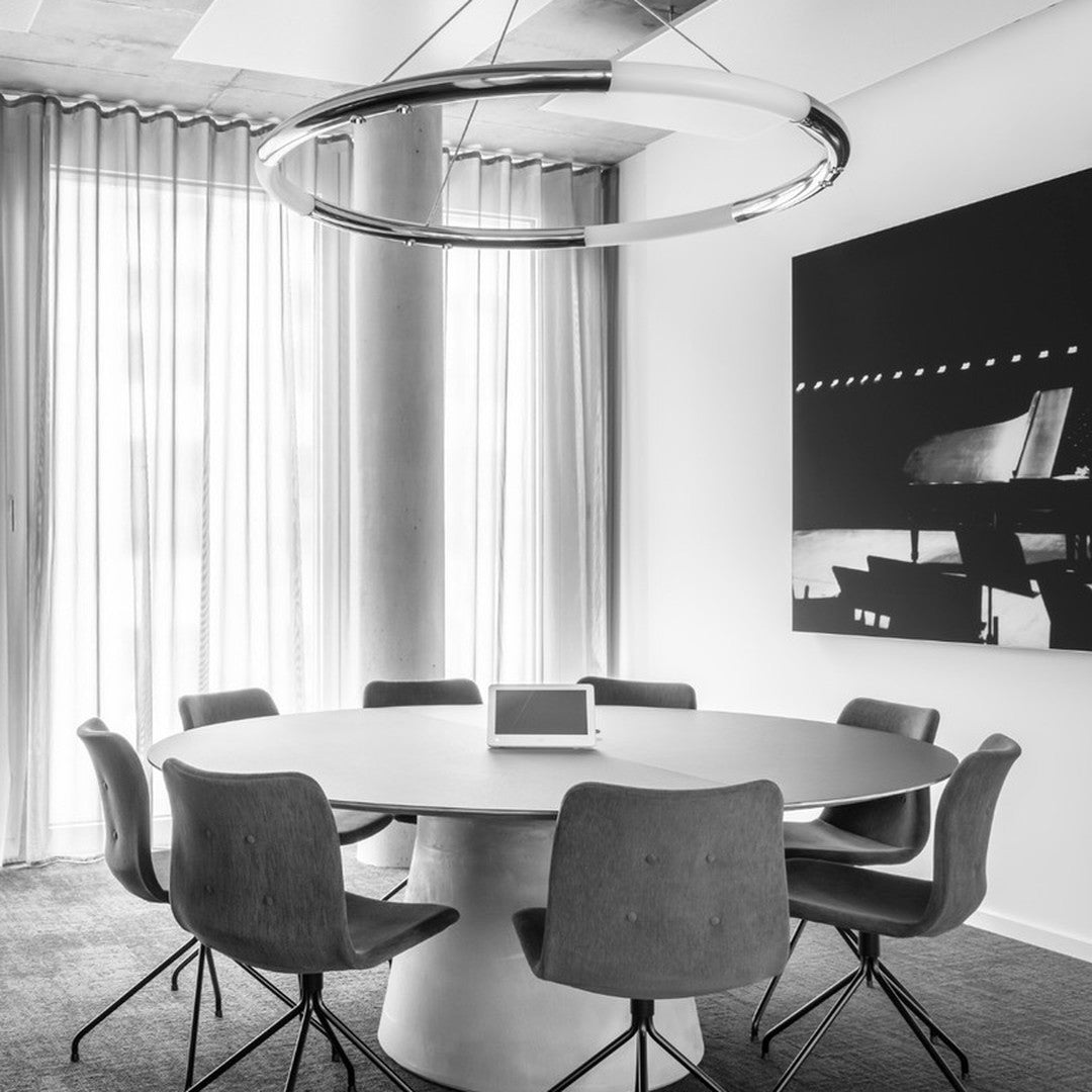 Modern round table surrounded by gray upholstered chairs in a sleek black-and-white meeting space.