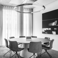 Modern round table surrounded by gray upholstered chairs in a sleek black-and-white meeting space.