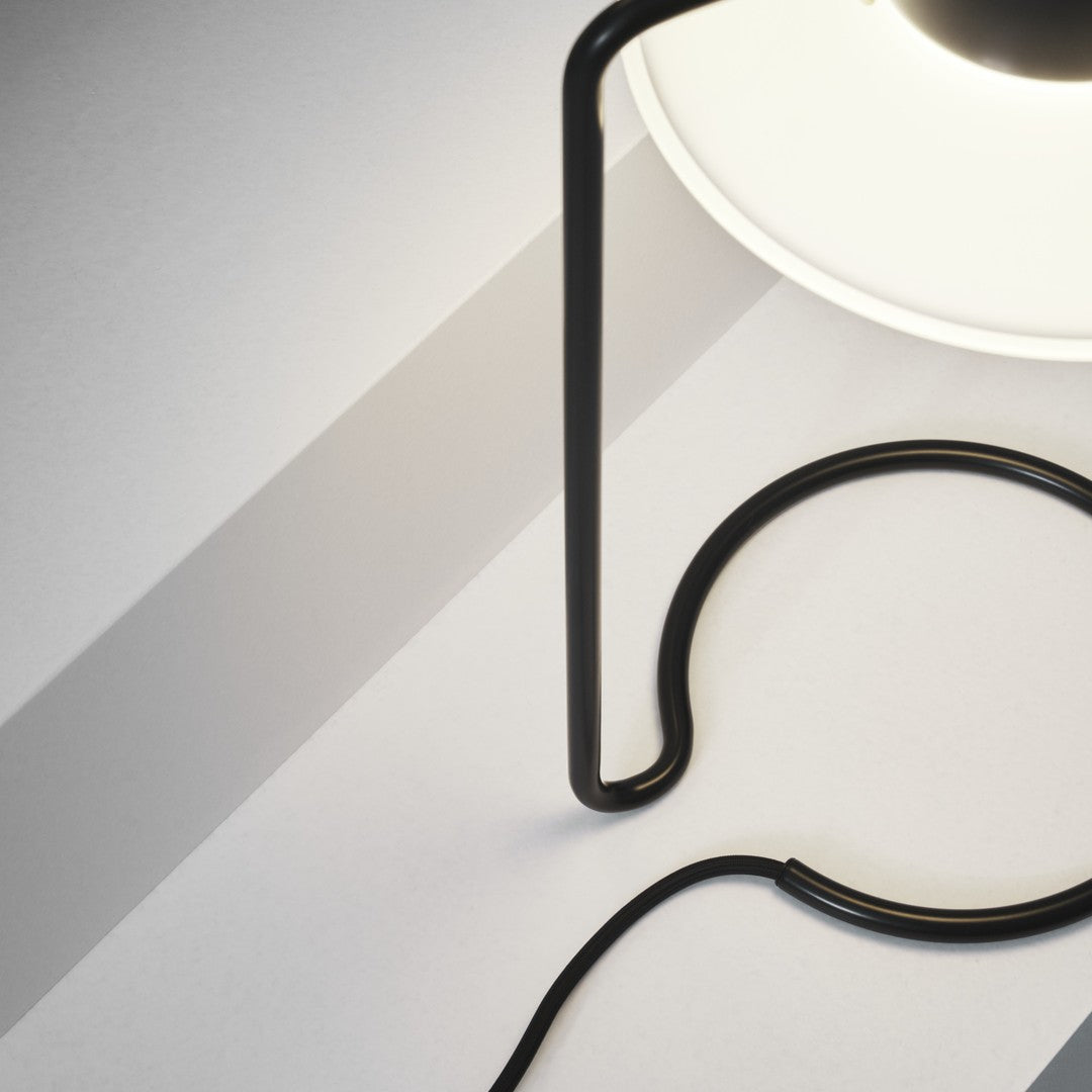 Modern black lamp with curved lines, featuring a white circular shade and sleek shadow patterns on a light gray surface.