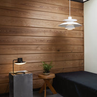 Modern bedroom featuring warm wood paneling, a white pendant lamp, and a black bedspread with simple, clean lines.