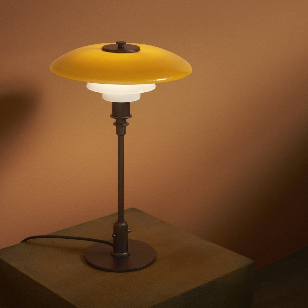 Stylish lamp with a yellow glass shade and a white frosted base on a sleek black metal stand.