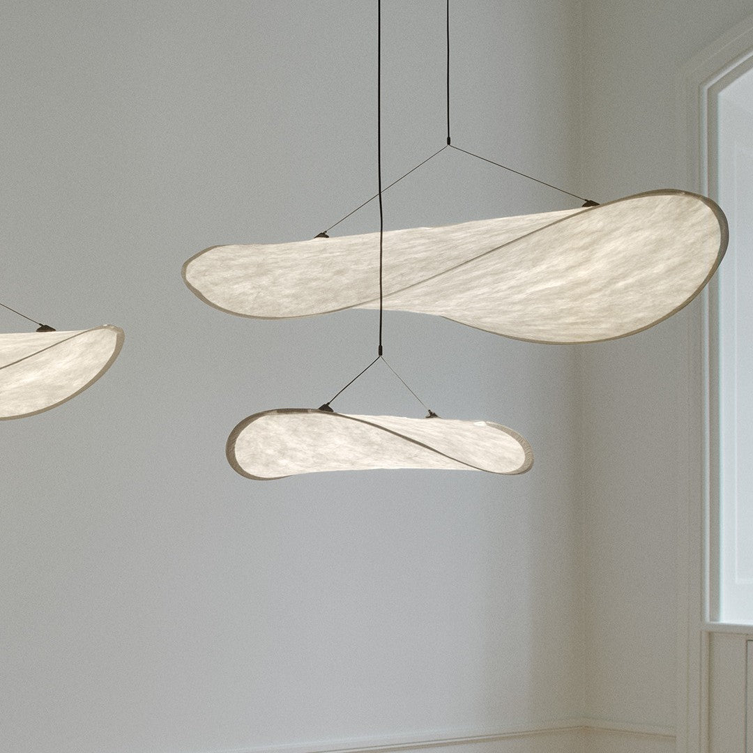 Abstract white pendant lights with soft curves, featuring a sleek, minimalist design against a light-colored wall.