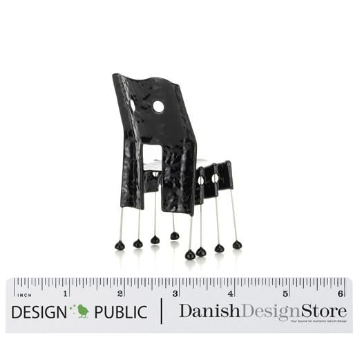 Black chair with a unique pattern and shiny silver legs, featuring distinctive cutouts and minimalist design.