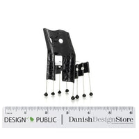 Black chair with a unique pattern and shiny silver legs, featuring distinctive cutouts and minimalist design.