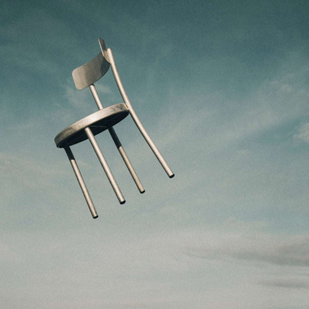 Light gray wooden chair with minimalistic design, contrasting against a soft blue sky. Floating in mid-air.